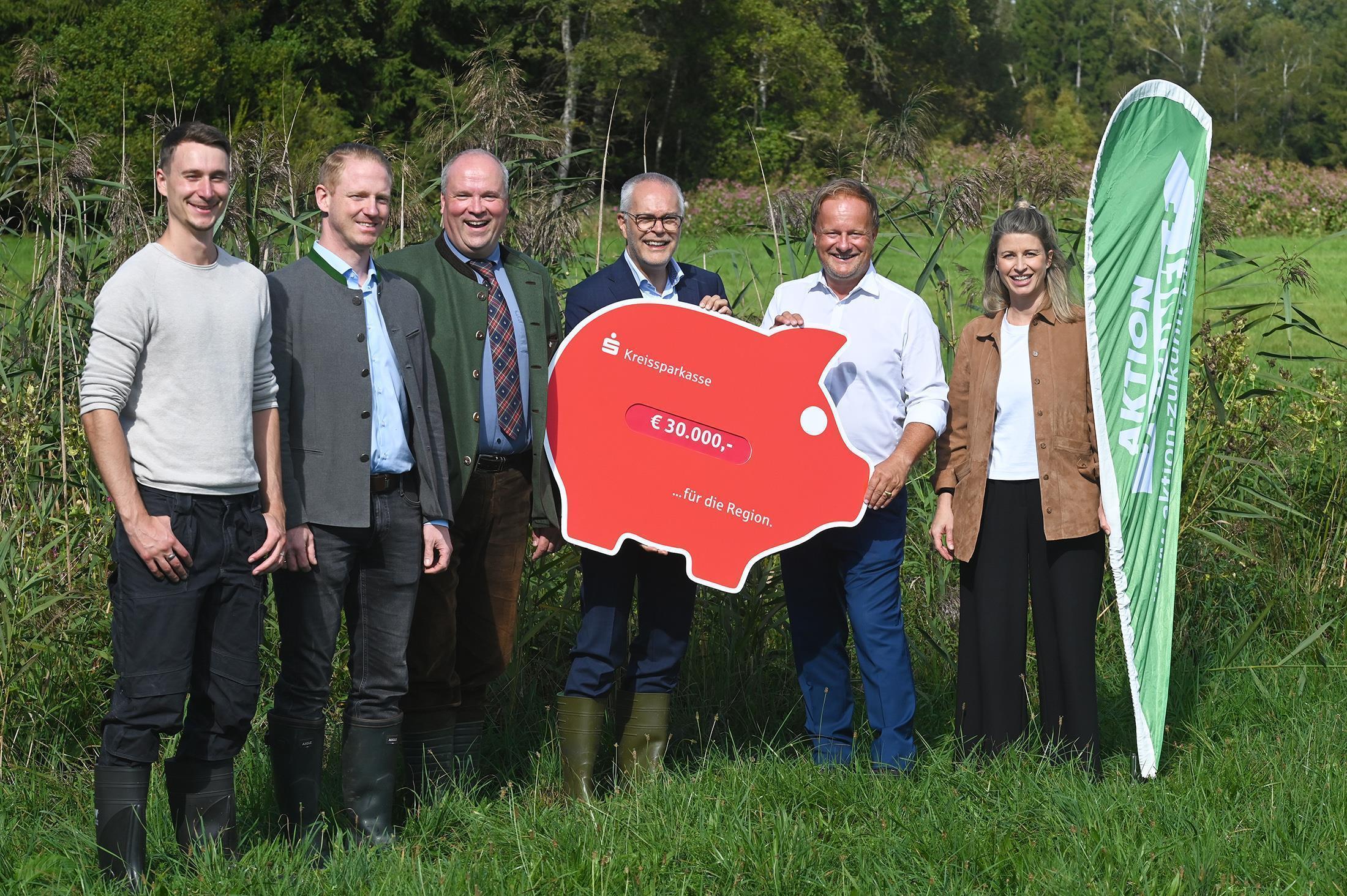 Andreas Frühschütz, Vorstandsvorsitzender der Kreissparkasse (3. v. r.), überreicht den symbolischen Scheck an die Landräte Robert Niedergesäß (2. v. r.) und Christoph Göbel (3. v. l.) sowie Dr. Willie Stiehler von der Energieagentur Ebersberg-München (2. v. l.), Jonas Galdirs, Geschäftsführer CO2-regio (ganz links) und Evelyn Reisner, Projektleiterin der Aktion Zukunft+ beim Landratsamt München (ganz rechts).
© Energieagentur Ebersberg-München.